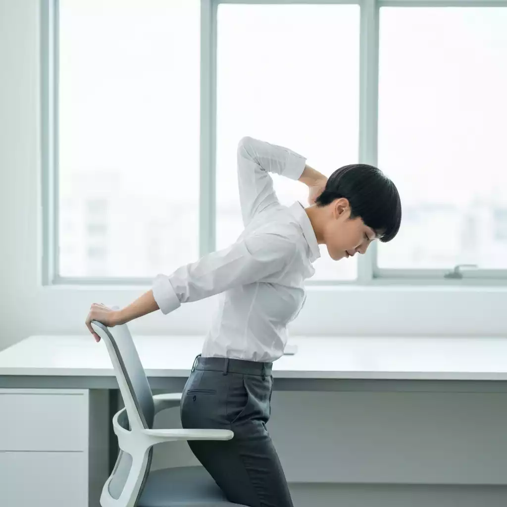 Office worker performing chair stretches at desk